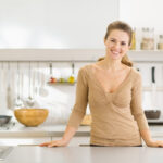 portrait of smiling young housewife in modern kitchen